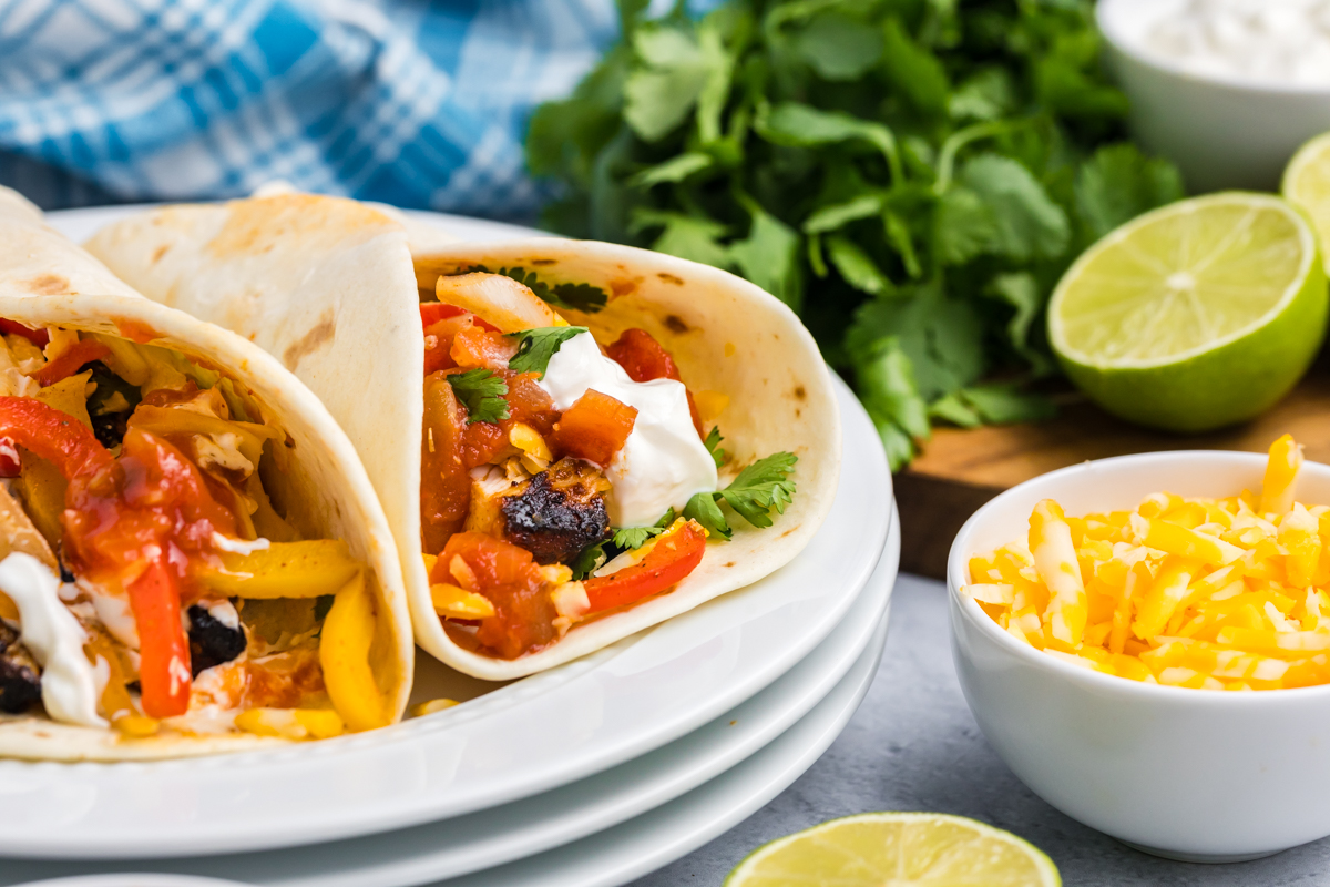 two grilled chicken fajitas on stack of plates