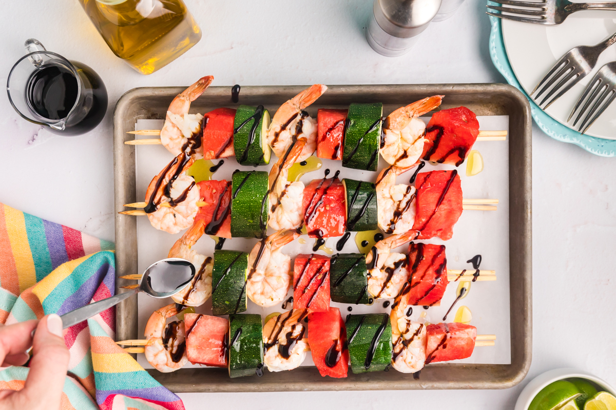 balsamic glaze drizzling over watermelon shrimp kabobs