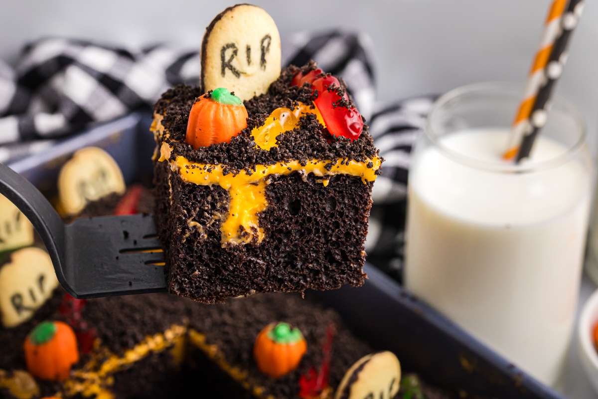 angled shot of slice of graveyard poke cake on spatula