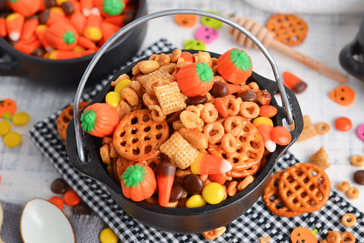 angle view of honey nut halloween snack mix in a small black cauldron