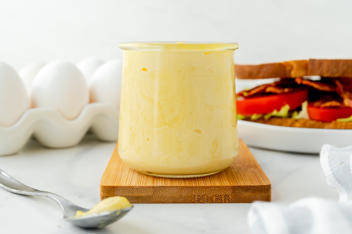 straight on shot of jar of homemade mayonnaise on wooden board