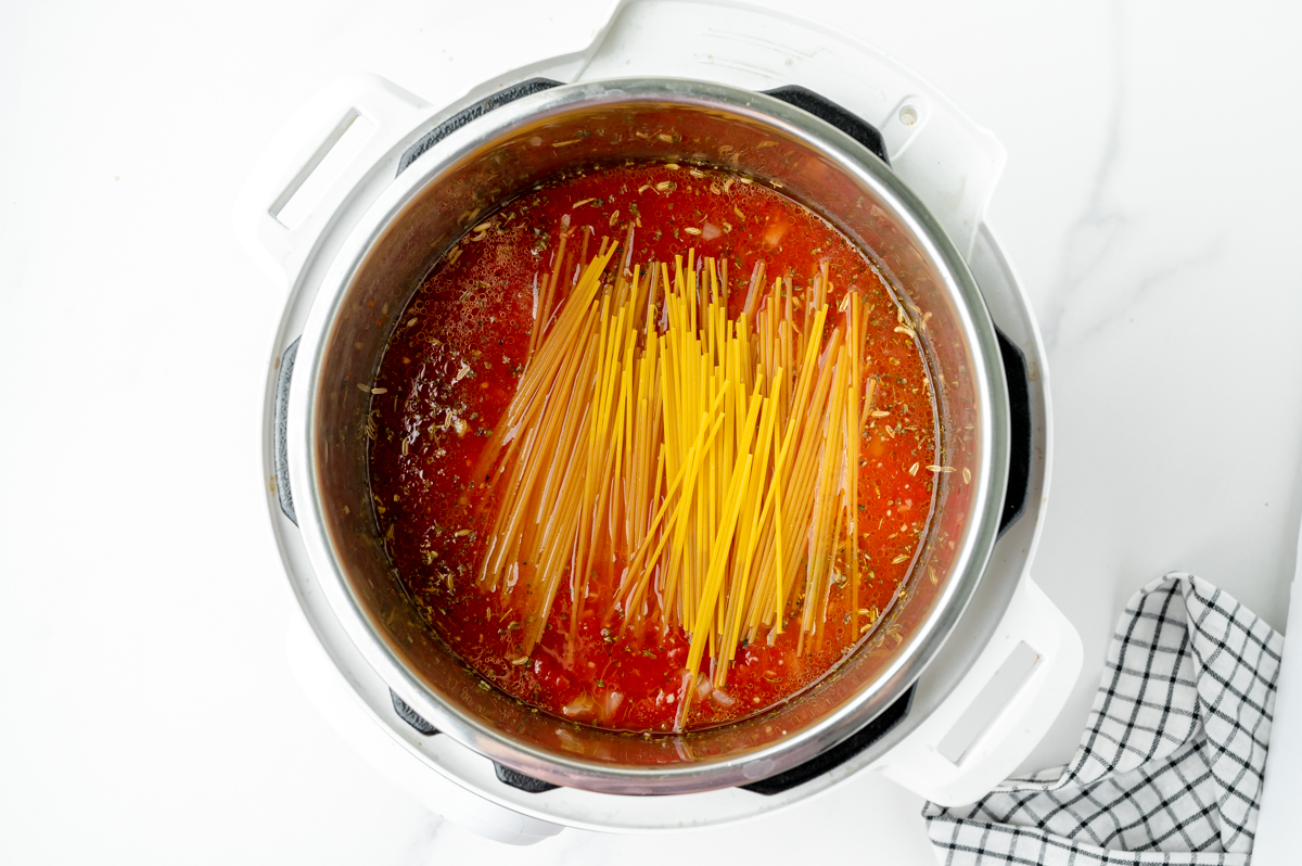 dry spaghetti added to instant pot of sauce