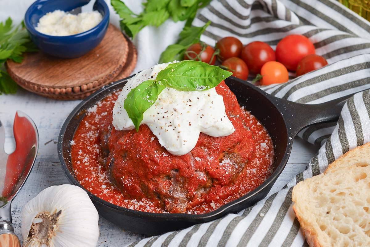 angled shot of jumbo meatball in cast iron skillet