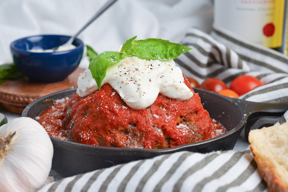 straight on shot of large meatball in cast iron skillet