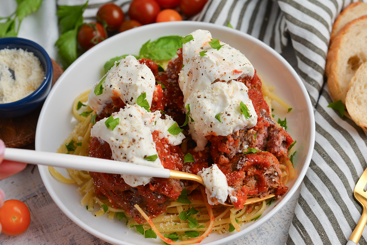 close up angled shot of cut up lavo one pound meatball over pasta in bowl