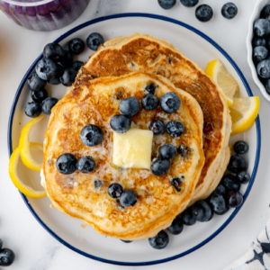 overhead shot of stack of pancakes topped with blueberries and butter