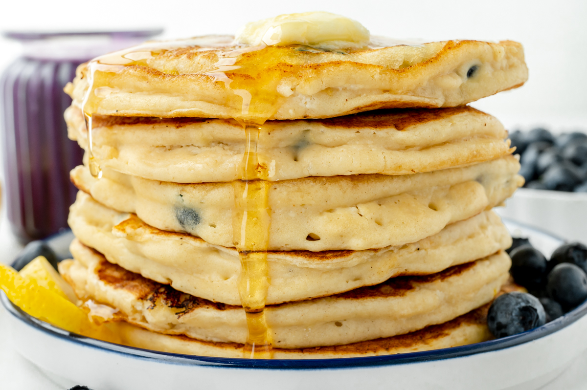 straight on shot of stack of lemon ricotta pancakes topped with maple syrup