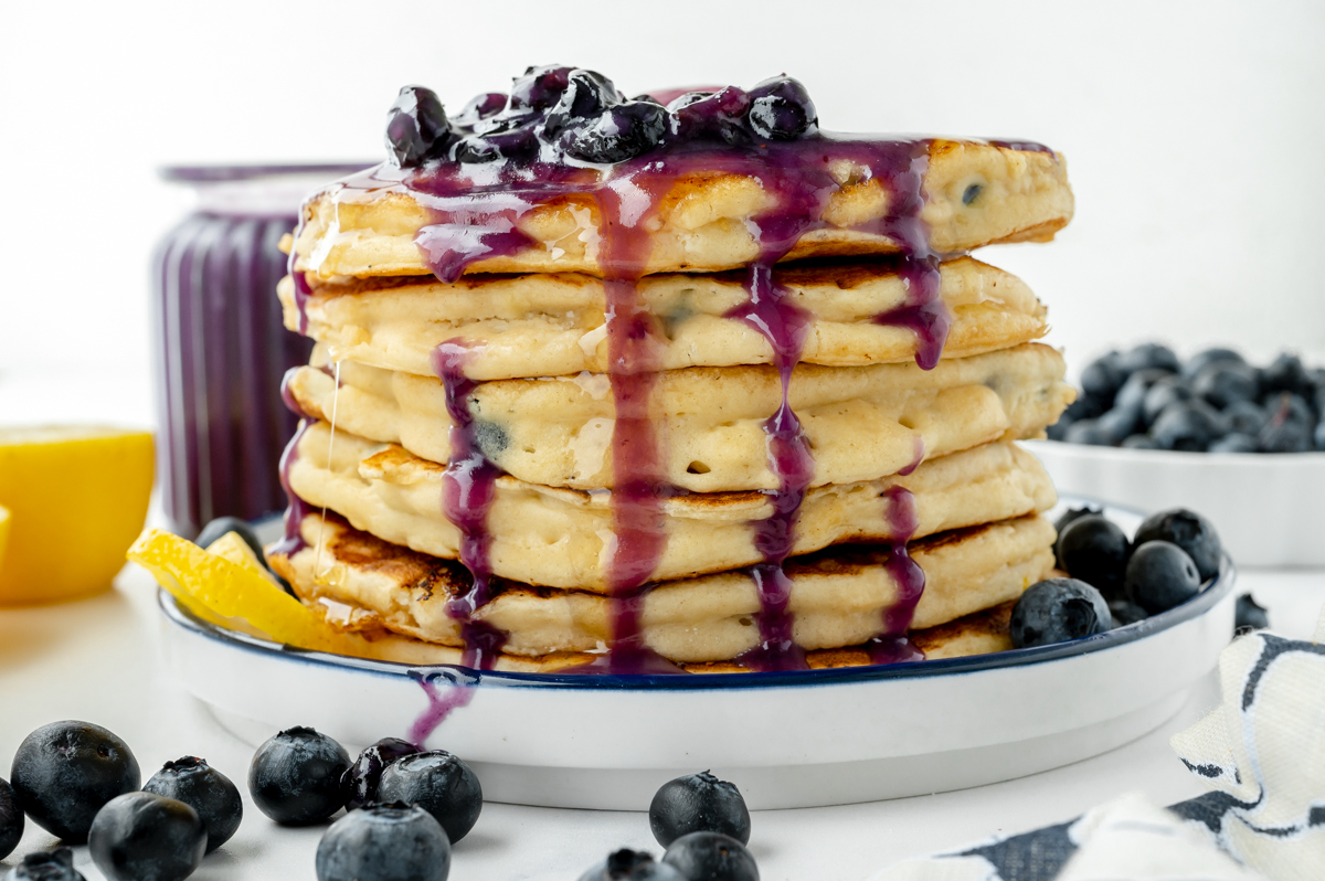 on shot of stack of lemon ricotta pancakes topped with blueberry syrup