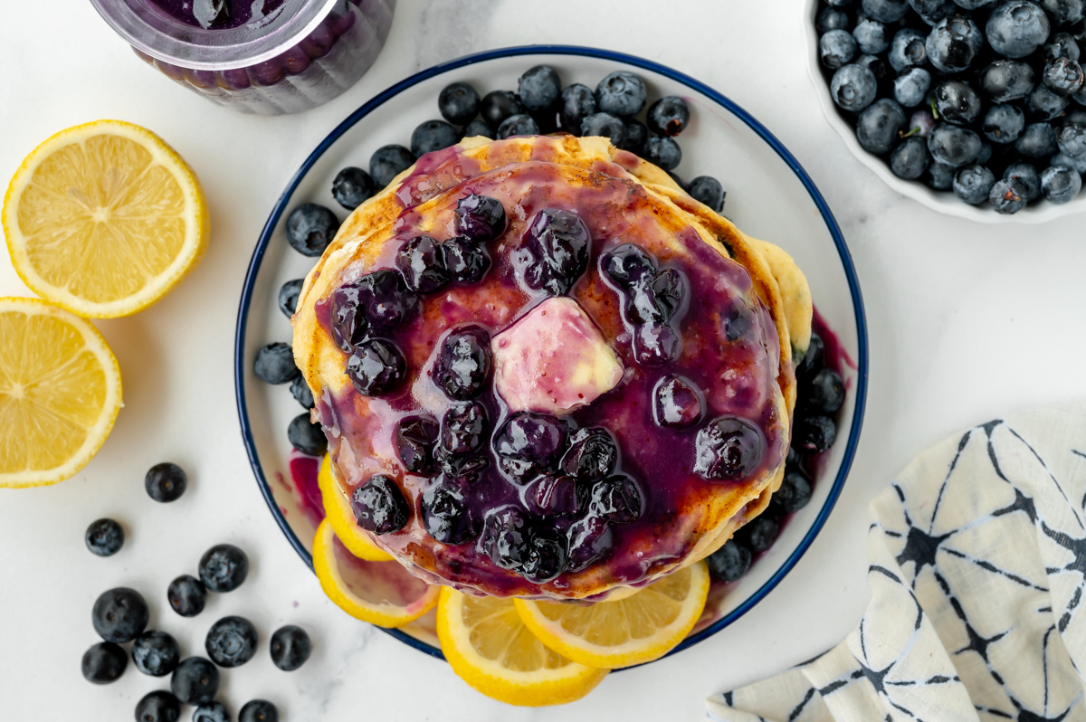 overhead shot of stack of pancakes topped with blueberry syrup