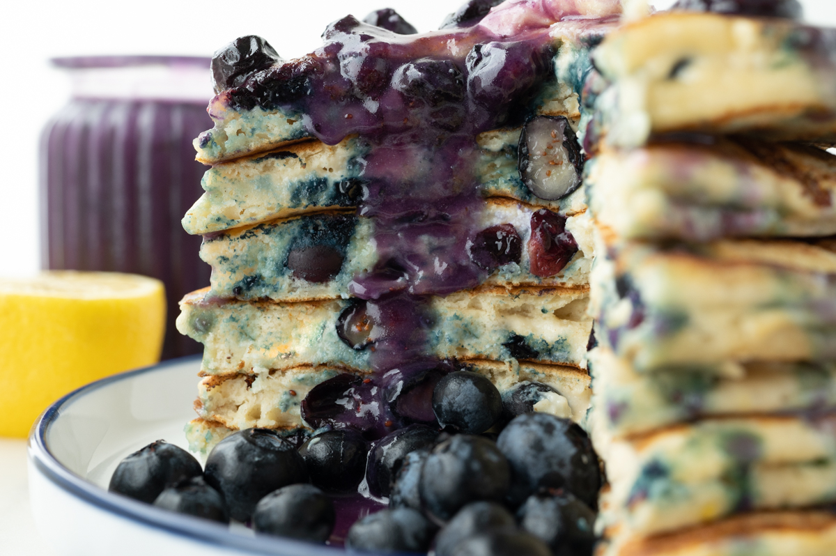 close up shot of bite taken out of stack of lemon blueberry pancakes