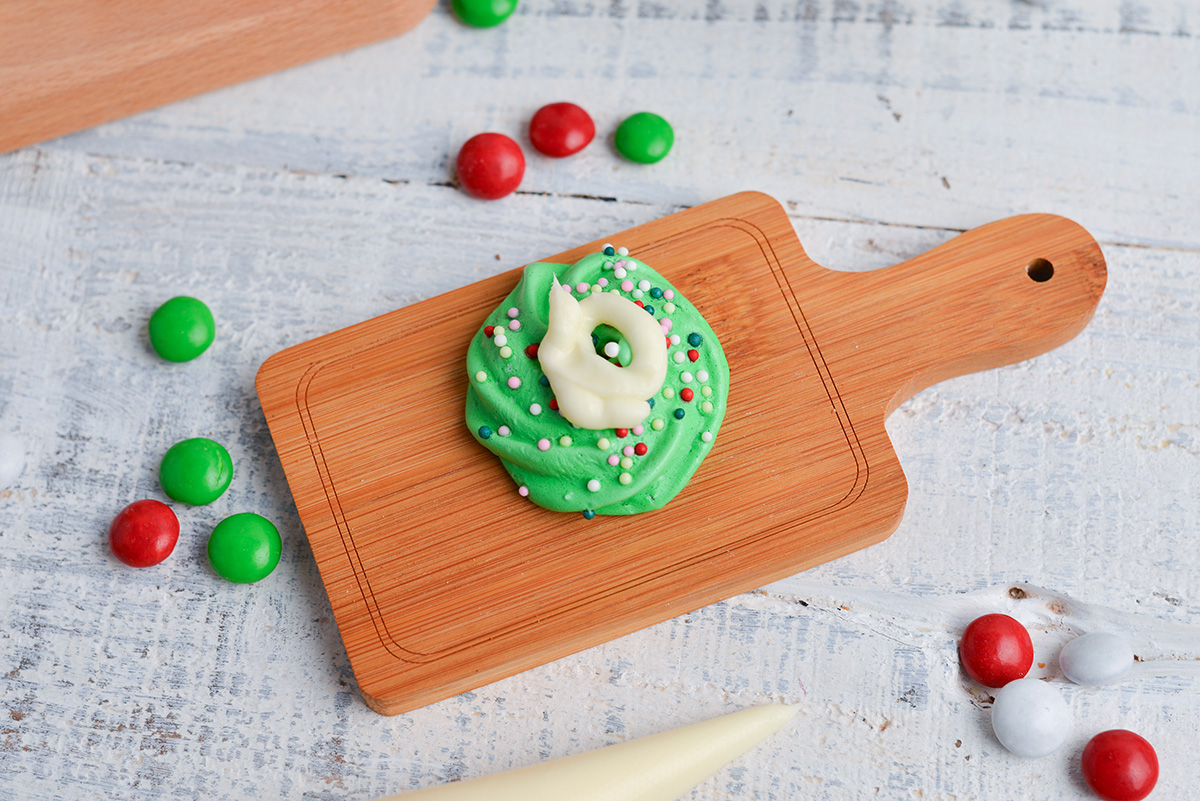 close up of meringue rosette with buttercream on small wood cutting board