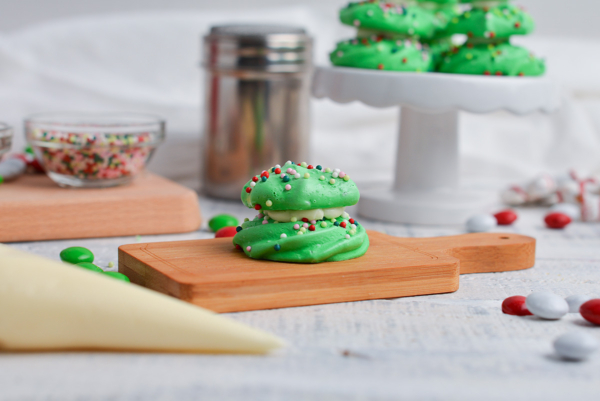 two meringue pieces stacked with buttercream on a small wooden cutting board