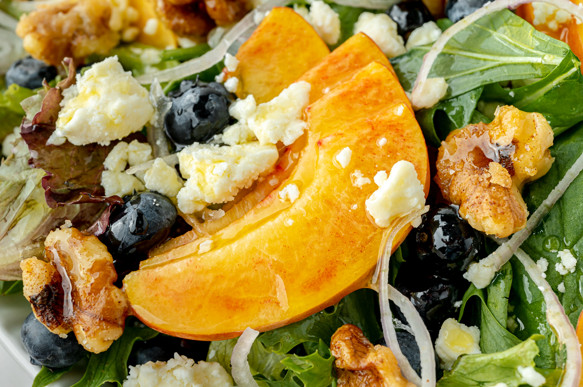 close up angled shot of sliced peaches on salad