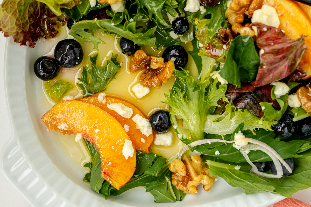 overhead shot of sliced peaches on plate of salad