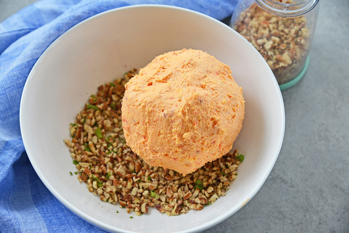 pimento cheese ball sitting in chopped walnuts