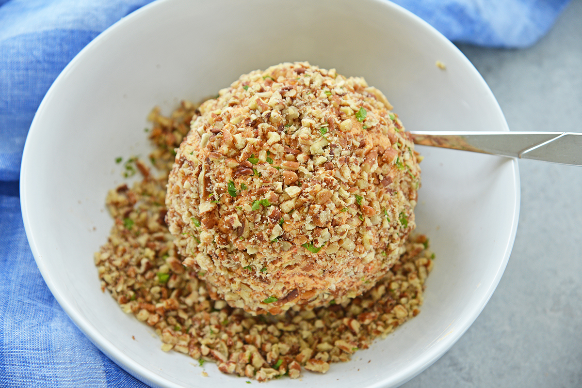 pimento cheese ball in a bowl of chopped walnuts