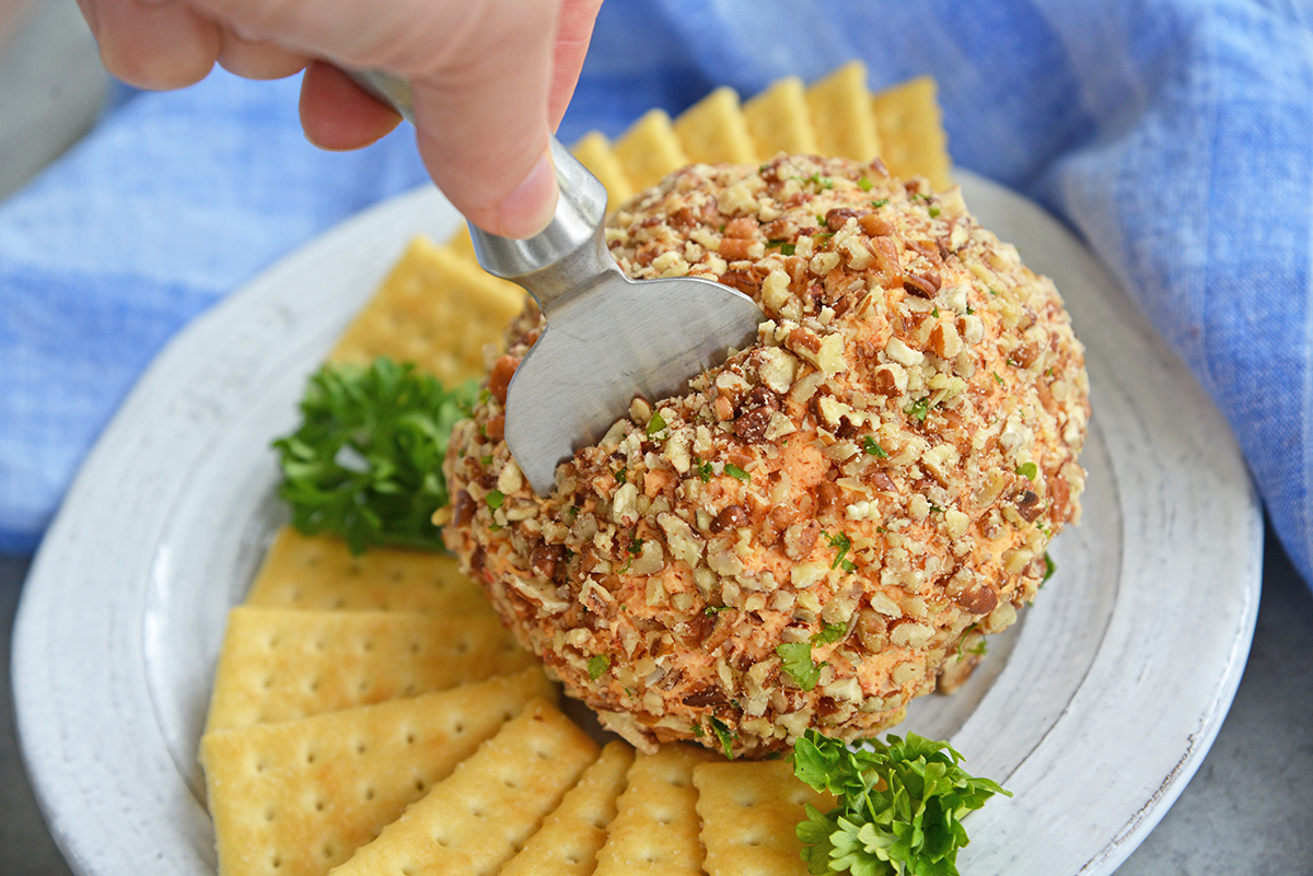 cheese knife cutting into a party cheese ball