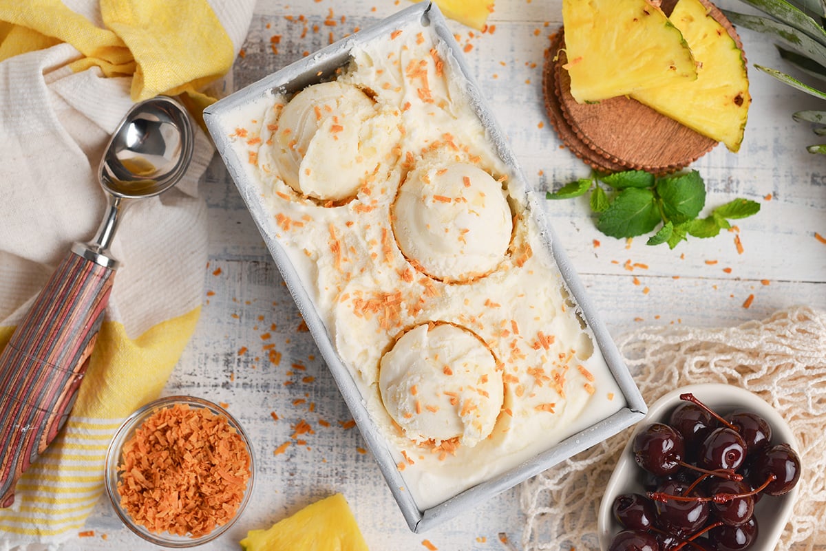 overhead shot of loaf pan of pina colada ice cream topped with toasted coconut