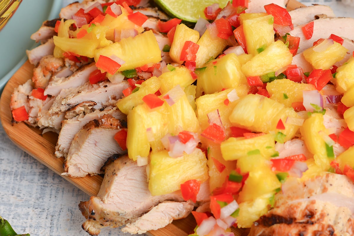 close up angled shot of pineapple salsa over chicken