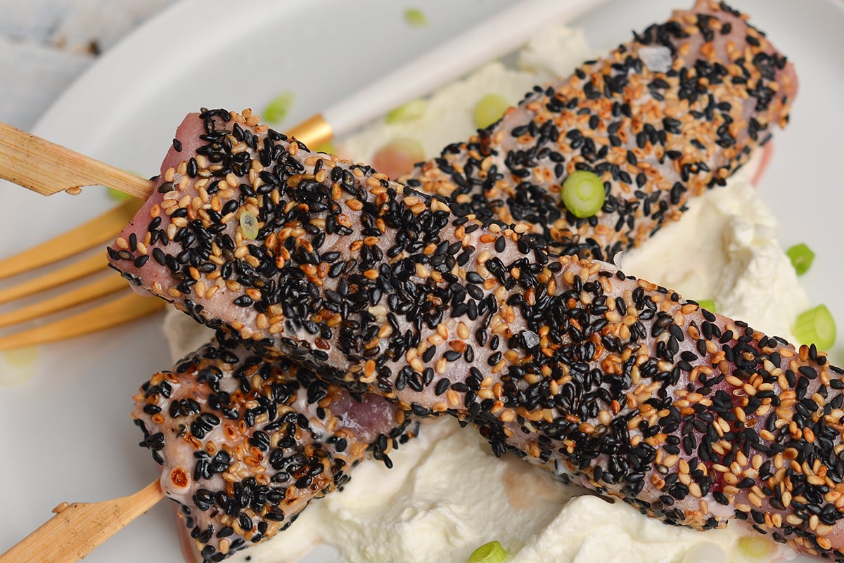 close up overhead shot of two sticks of sesame crusted tuna on a plate