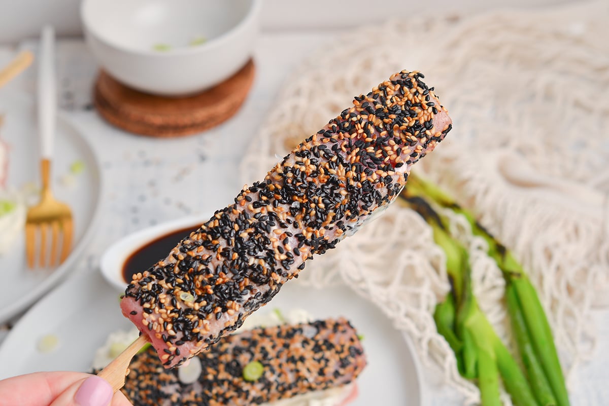 hand holding sesame crusted tuna on a stick