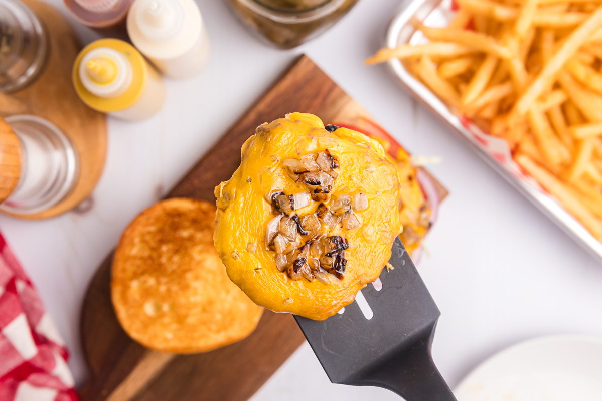 overhead shot of cheeseburger patty on spatula