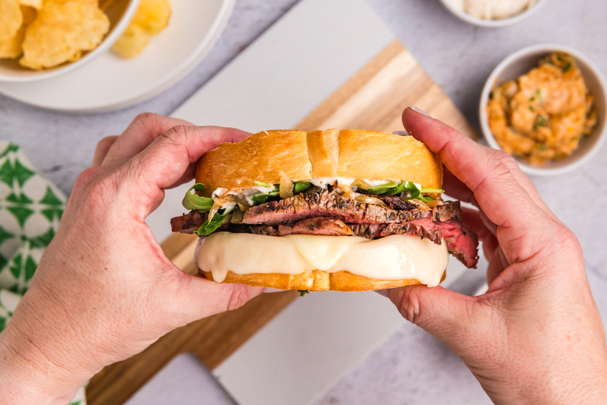 overhead shot of hands holding steak sandwich