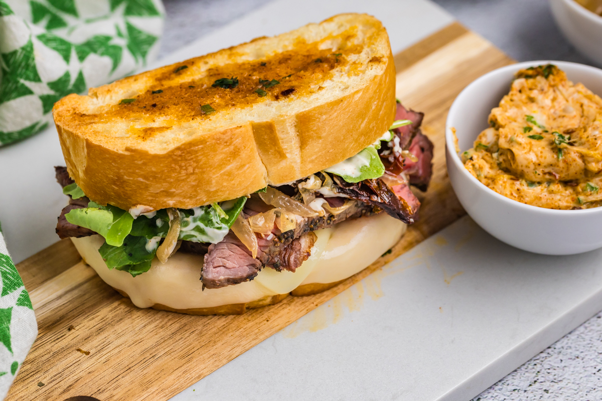 angled shot of steak sandwich on cutting board