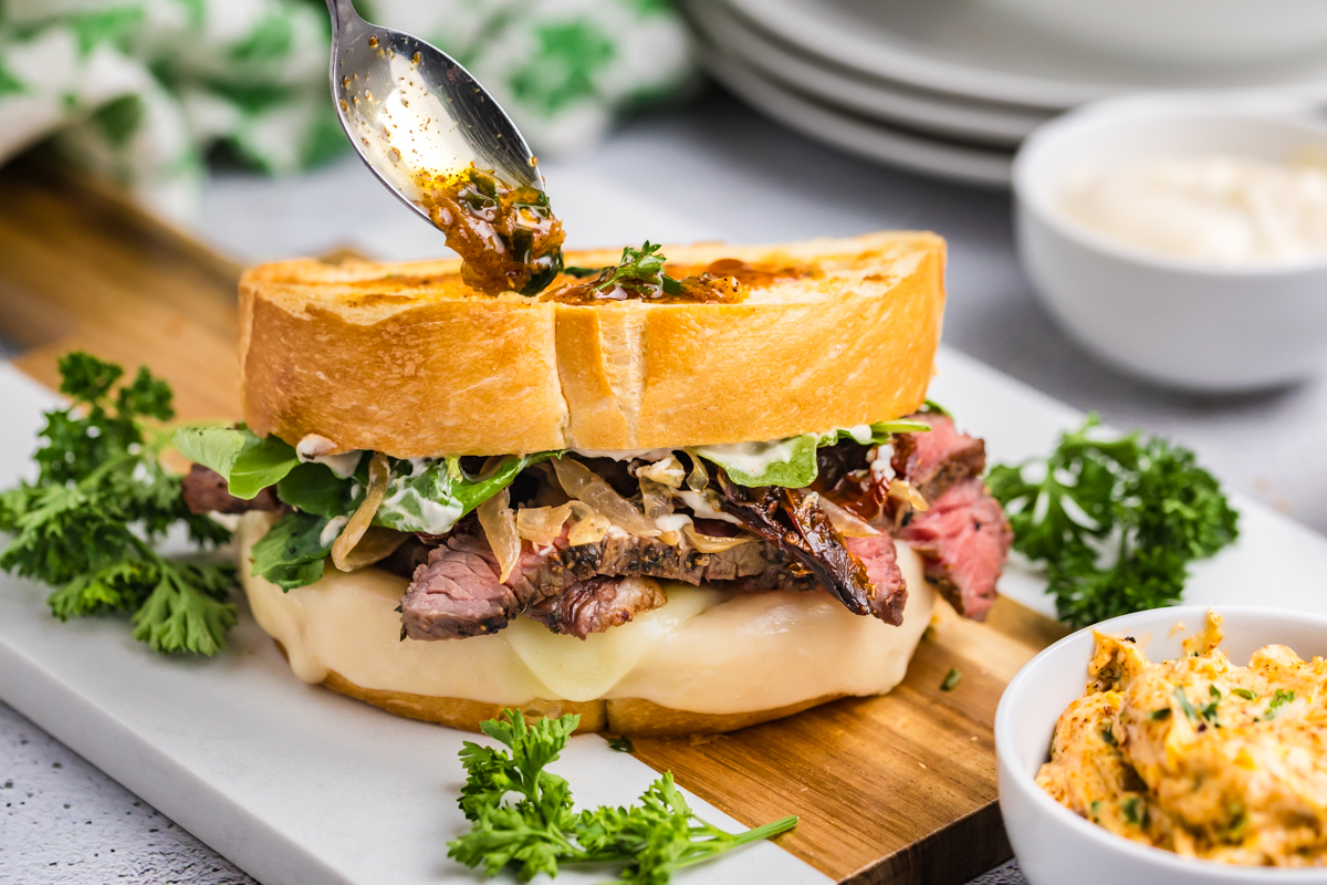 spoon adding cowboy butter to steak sandwich