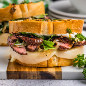 two steak sandwiches on cutting board