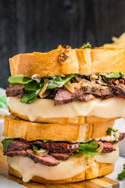 stack of two steak sandwiches on cutting board