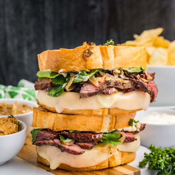 stack of two steak sandwiches on cutting board