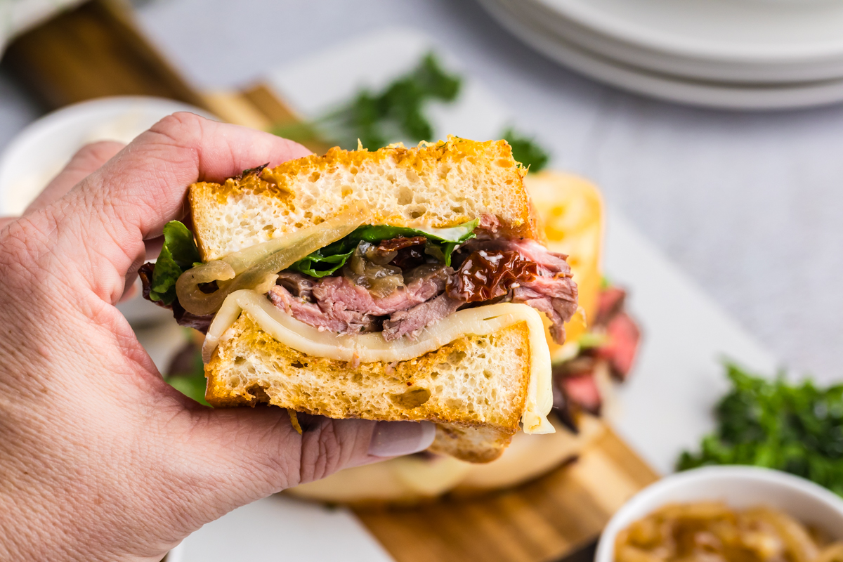 hand holding one steak sandwich half