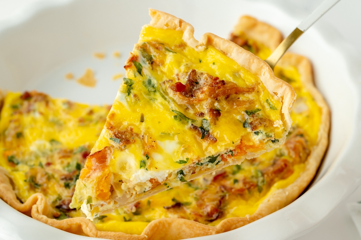 angled shot of slice of quiche on spatula