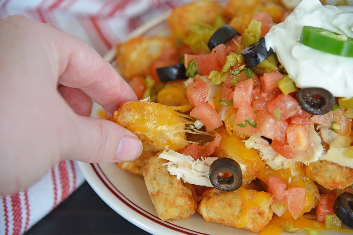 Hand pulling a cheesy tater tot