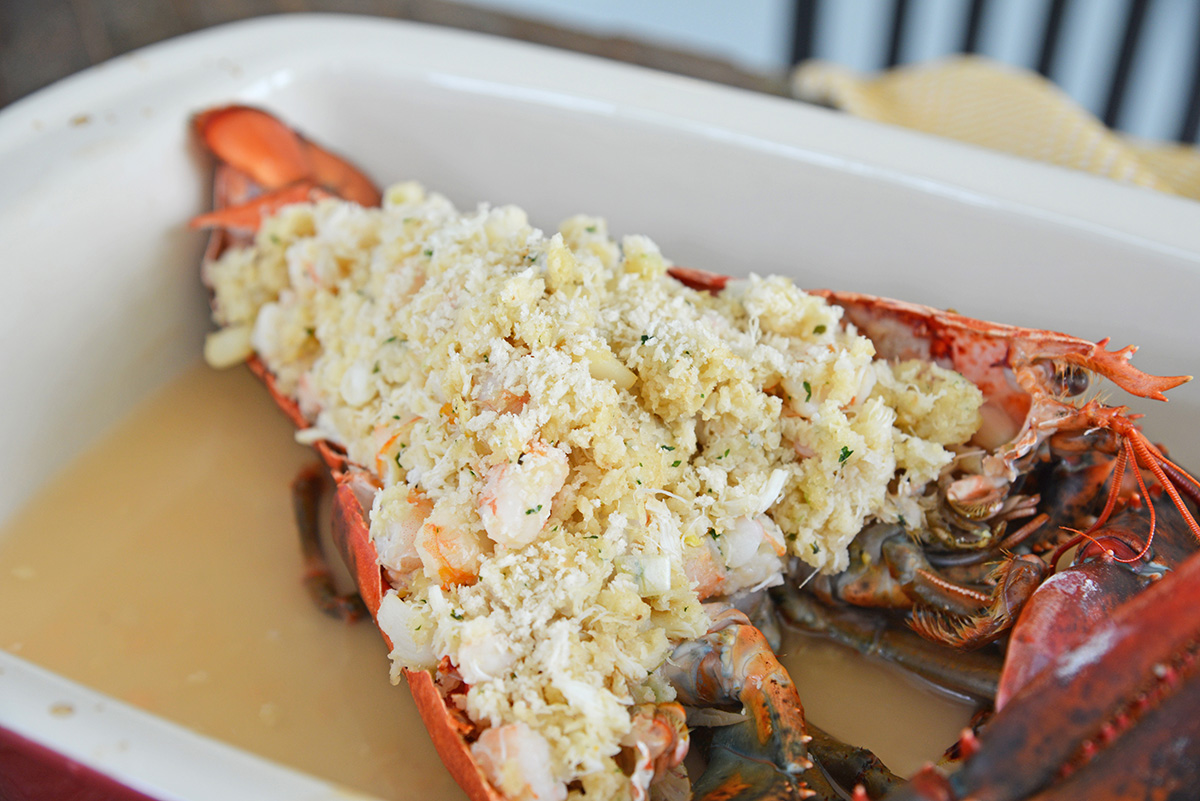 angled shot of whole stuffed lobster uncooked in baking dish