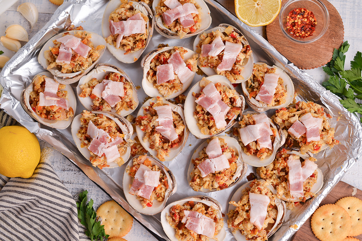 overhead shot of clams shells topped with stuffing on baking sheet