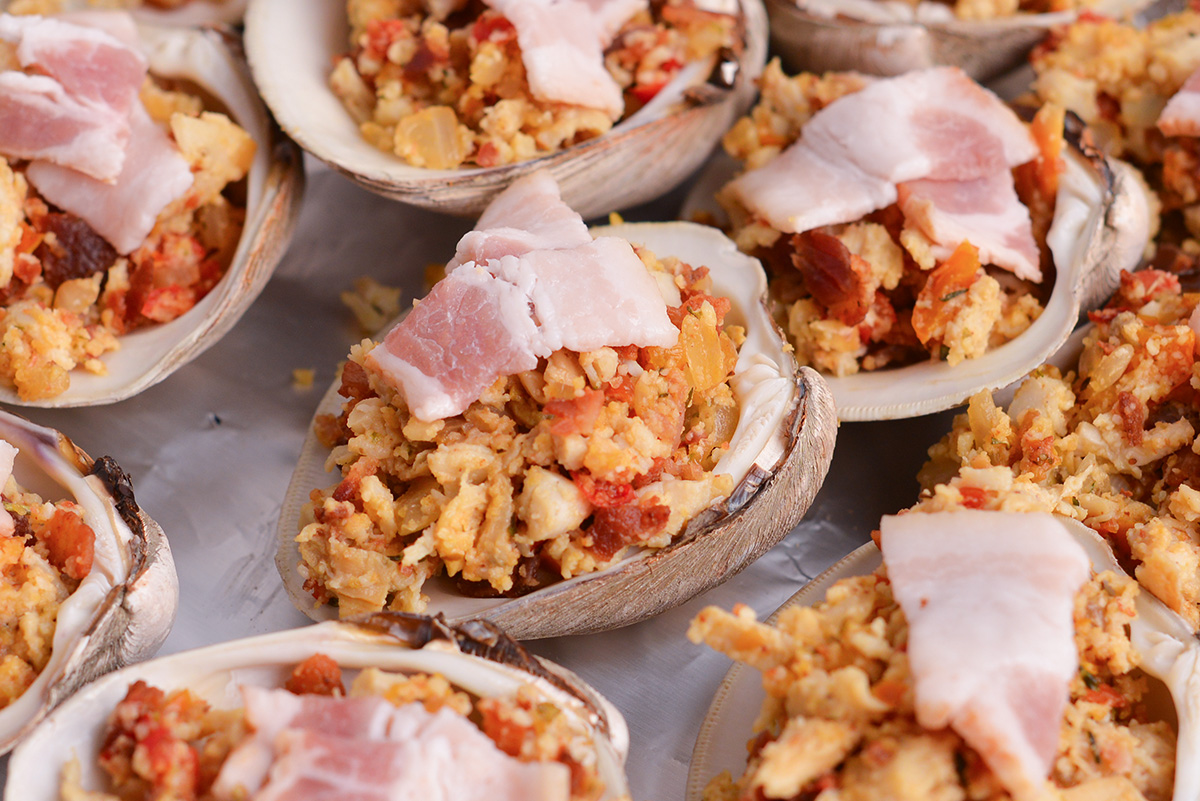 angled shot of raw clams casino on baking sheet