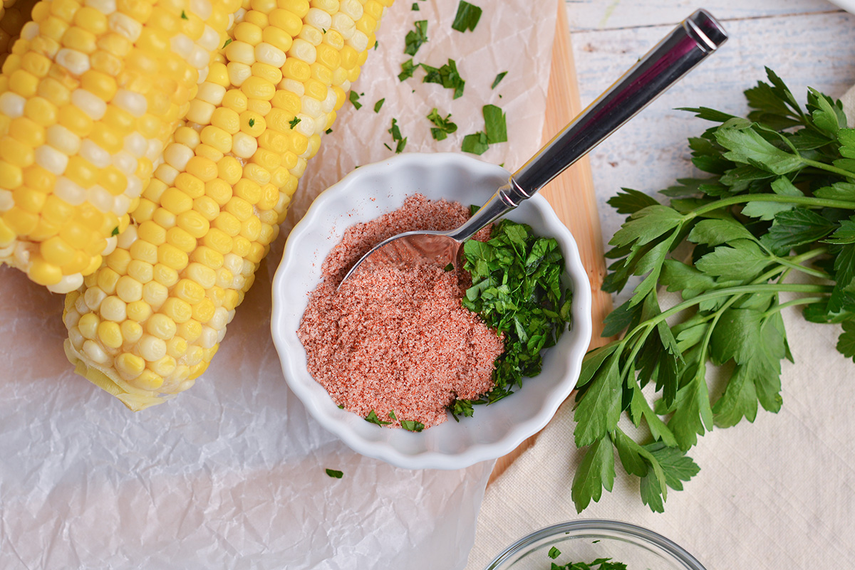 overhead shot of spoon in bowl of corn on the cob seasoning