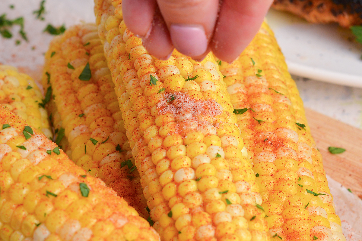 close up shot of seasoning sprinkled onto corn on the cob