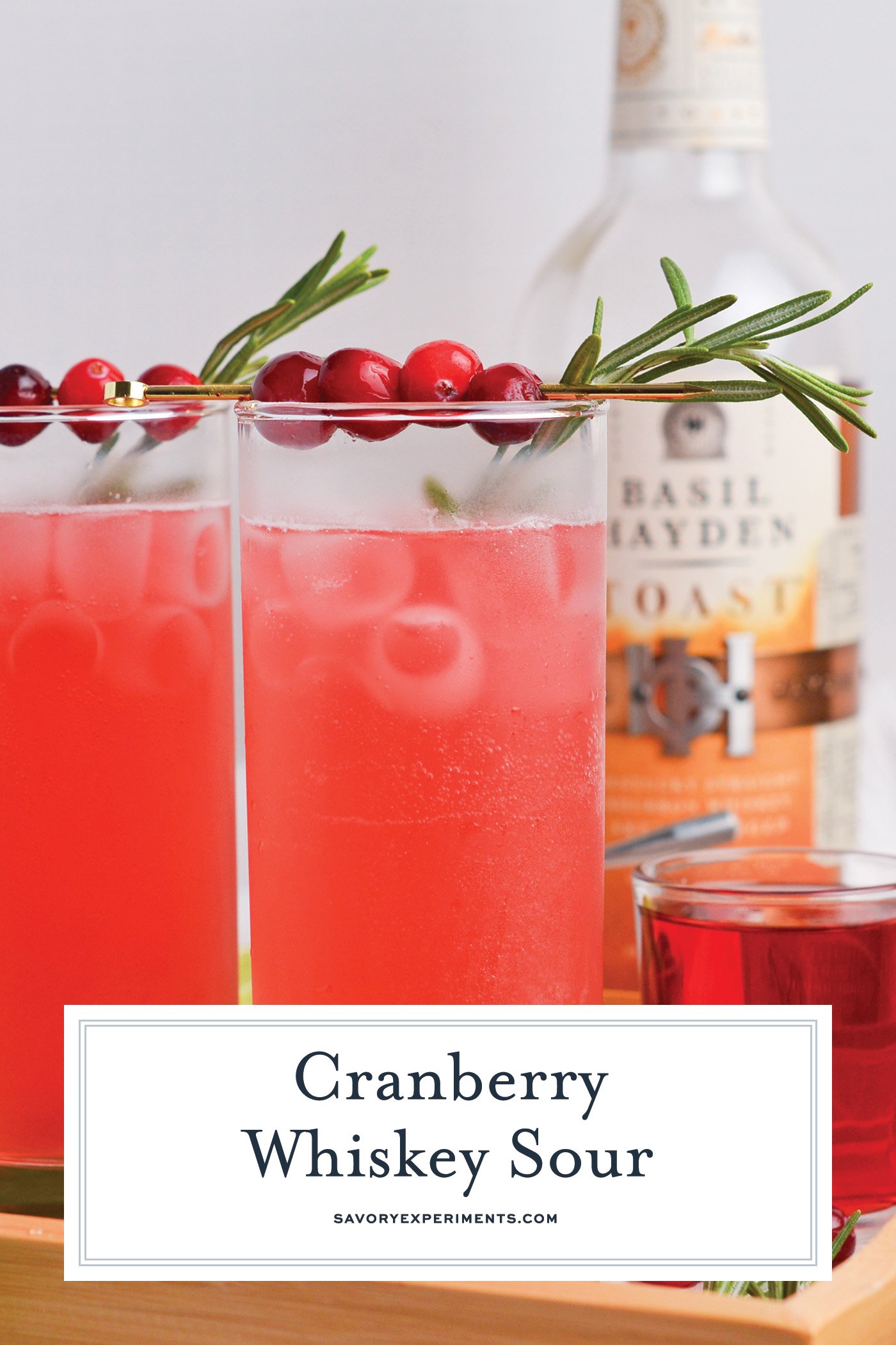 straight on shot of two cranberry whiskey sour cocktails with text overlay