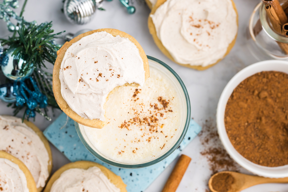 overhead shot of bit taken out of eggnog cookie on glass of eggnog