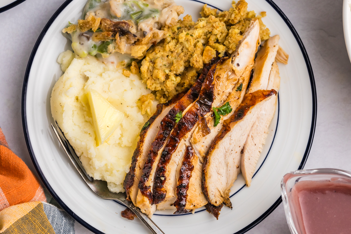 overhead shot of sliced turkey on plate with stuffing and mashed potatoes