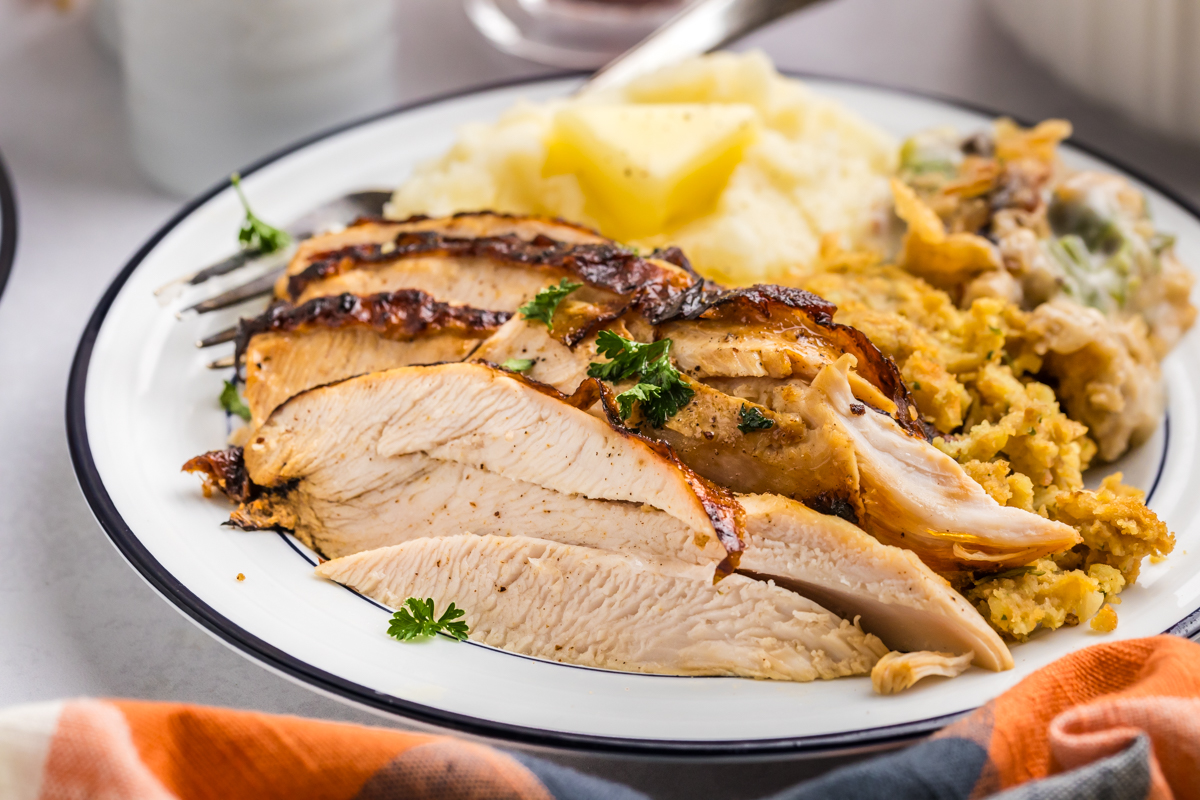 angled shot of sliced turkey on plate with stuffing and potatoes