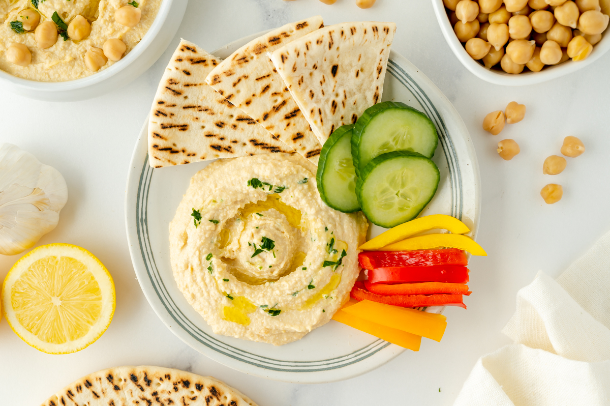 overhead shot of plate of homemade hummus with veggies and pita