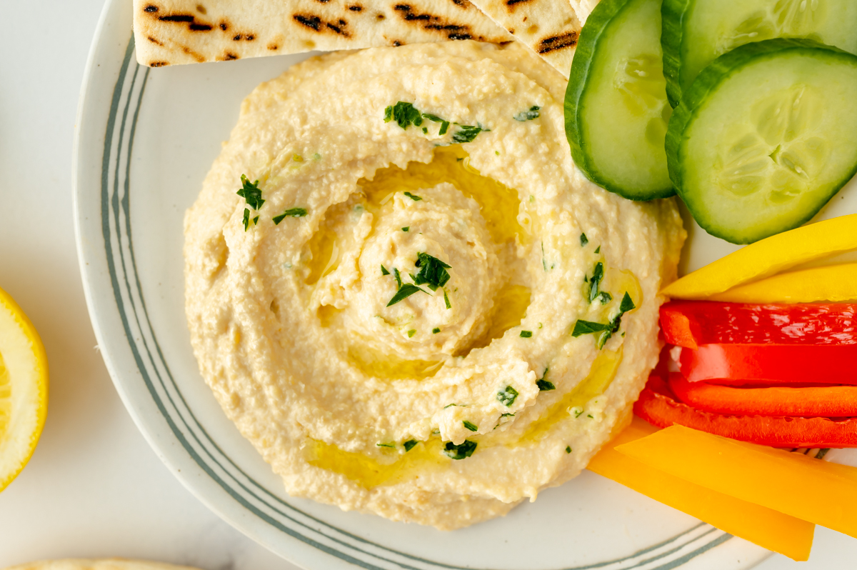 overhead shot of hummus on a plate with pita and veggies