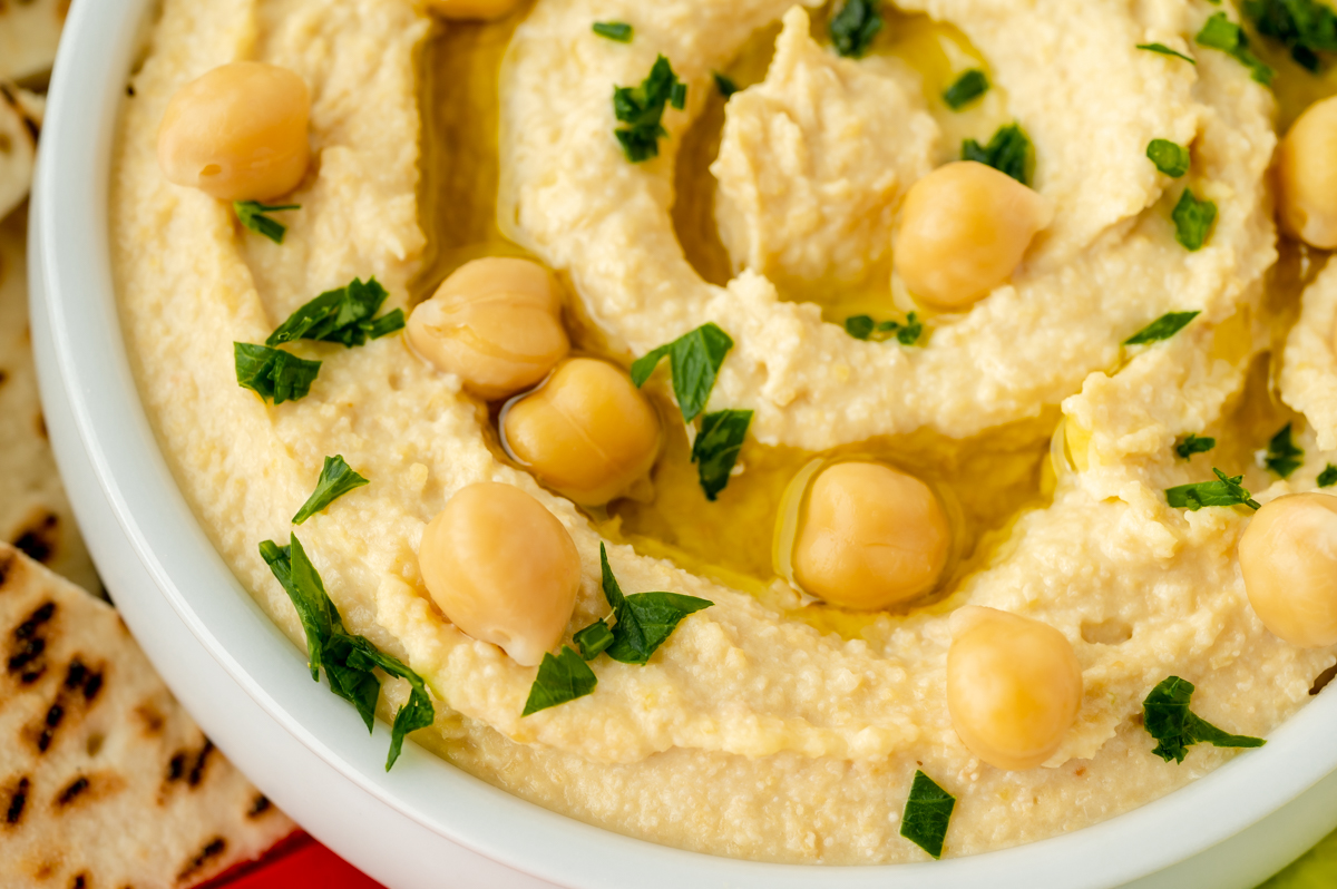 close up shot of chickpeas and olive oil on bowl of hummus