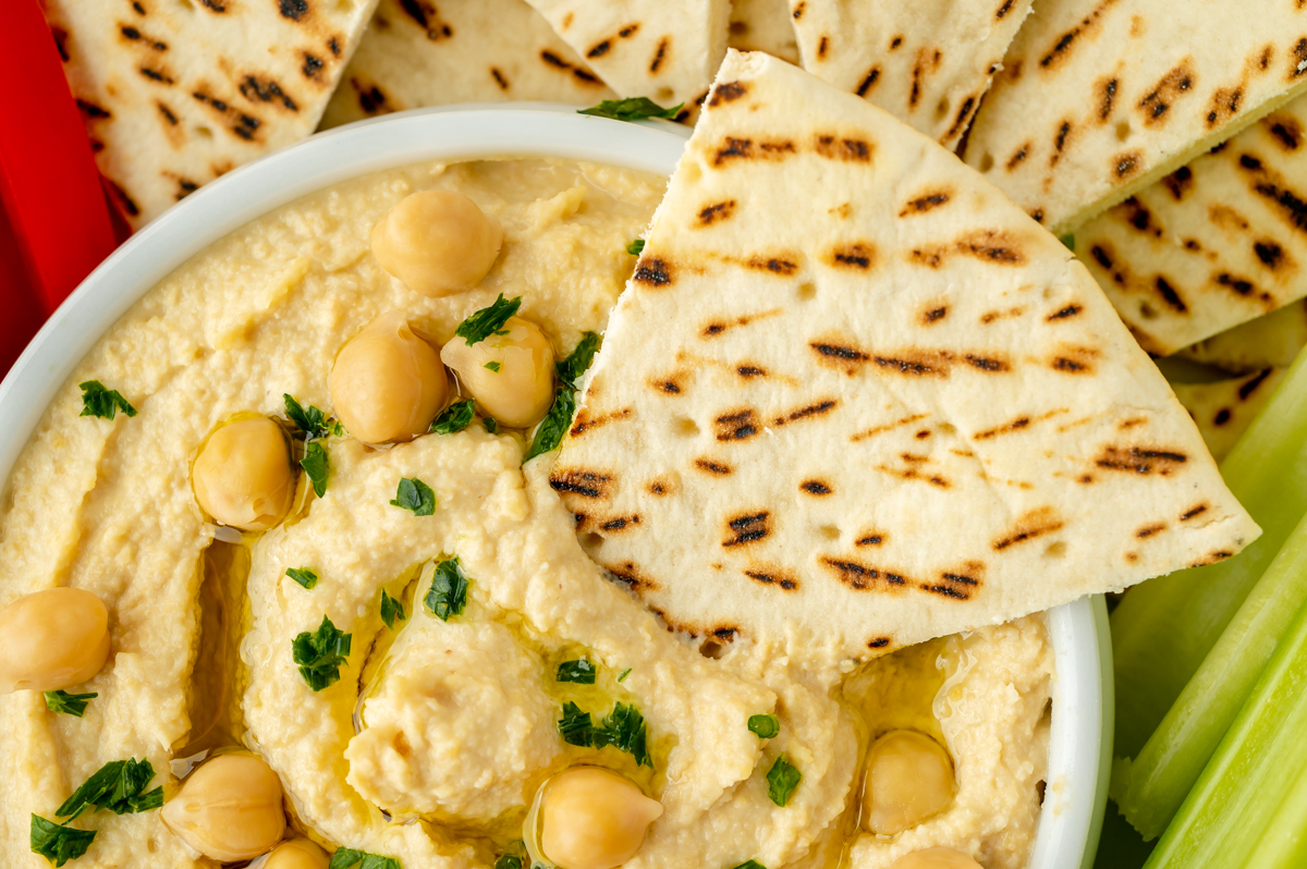 pita slice dipping into bowl of hummus