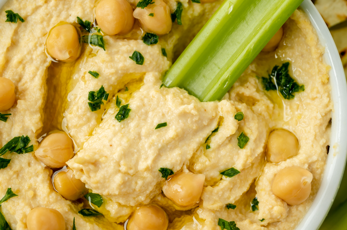 celery dipping into bowl of hummus