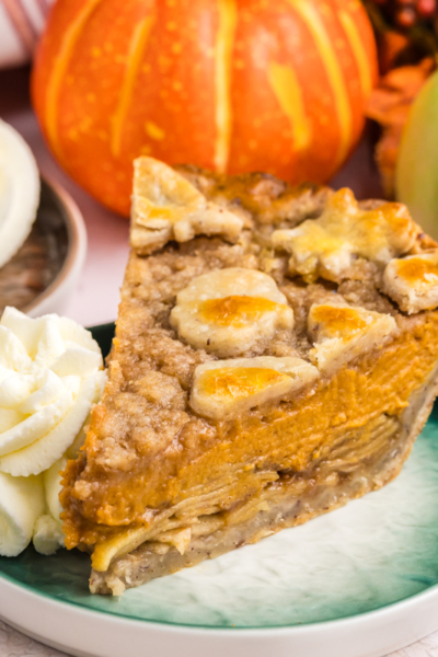 angled shot of slice of pumpkin apple pie on plate with whipped cream